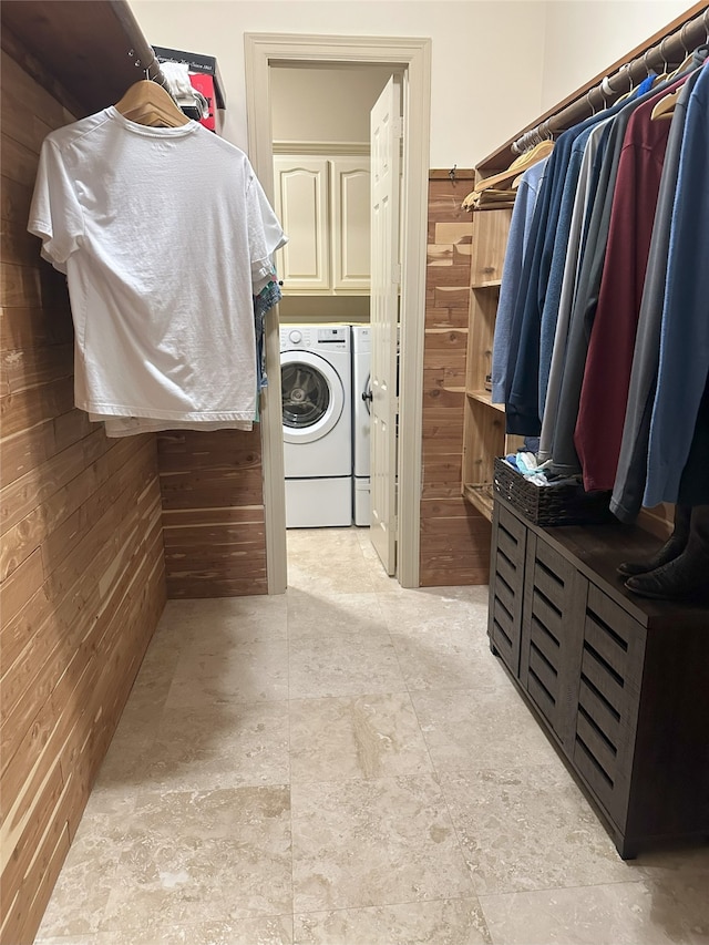 1302 Royal Sands Ln, Houston, TX 77345 - washroom with wooden walls, washing machine and clothes dryer, cabinet space, and light stone finish flooring