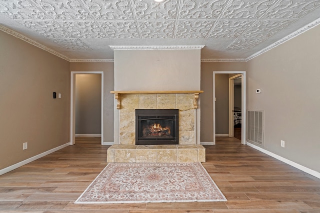 15110 Falling Creek Dr, Houston, TX 77068 - unfurnished living room with an ornate ceiling, wood finished floors, ornamental molding, a tiled fireplace, and baseboards