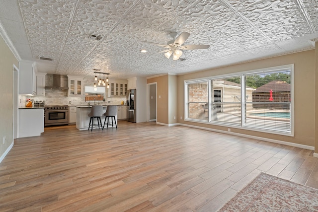 15110 Falling Creek Dr, Houston, TX 77068 - living area featuring light wood-type flooring, a ceiling fan, baseboards, an ornate ceiling, and crown molding