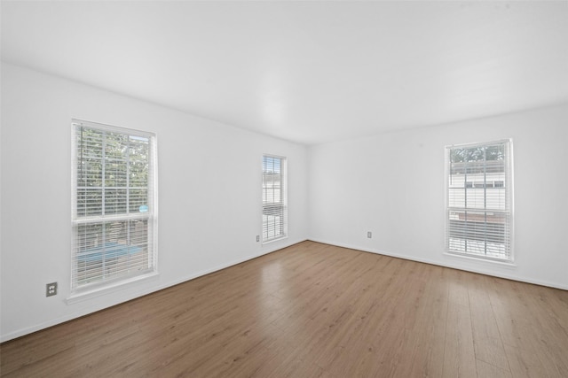 spare room with baseboards and wood finished floors