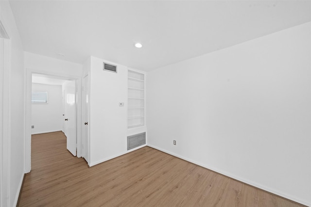 unfurnished bedroom with visible vents, light wood-style floors, and baseboards