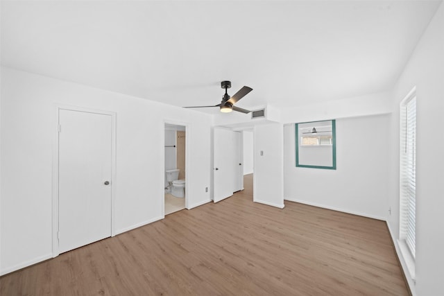 unfurnished bedroom with ceiling fan, visible vents, wood finished floors, baseboards, and ensuite bathroom