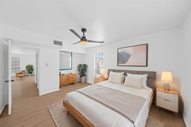 bedroom featuring a ceiling fan, baseboards, visible vents, and light wood-style flooring