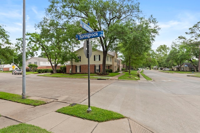 view of road with traffic signs, a residential view, curbs, and sidewalks
