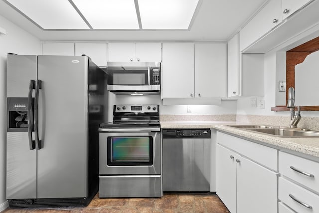 kitchen featuring white cabinets, light countertops, appliances with stainless steel finishes, and a sink