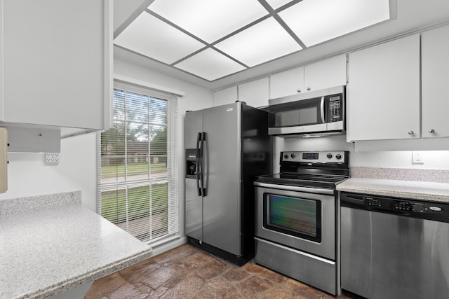 kitchen with white cabinetry, light countertops, stone finish flooring, and appliances with stainless steel finishes