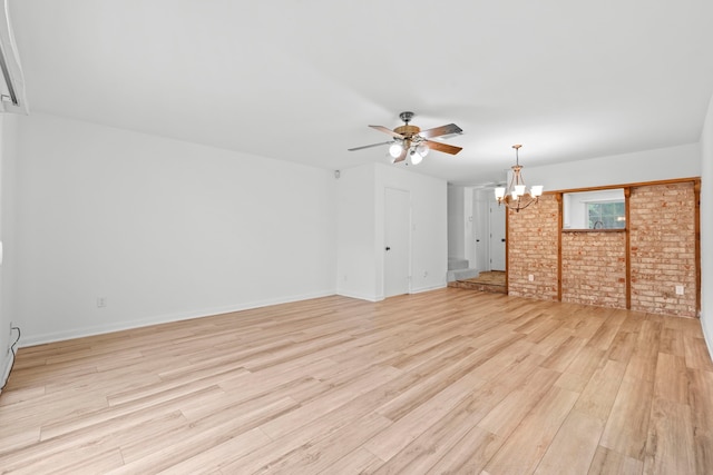 unfurnished living room featuring brick wall, ceiling fan with notable chandelier, baseboards, and light wood-style floors