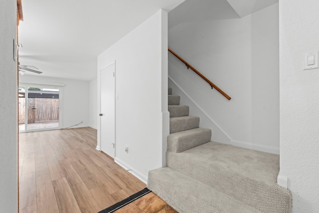 staircase featuring baseboards, ceiling fan, and wood finished floors