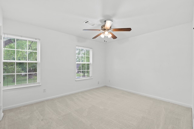 empty room featuring baseboards, ceiling fan, light carpet, and visible vents