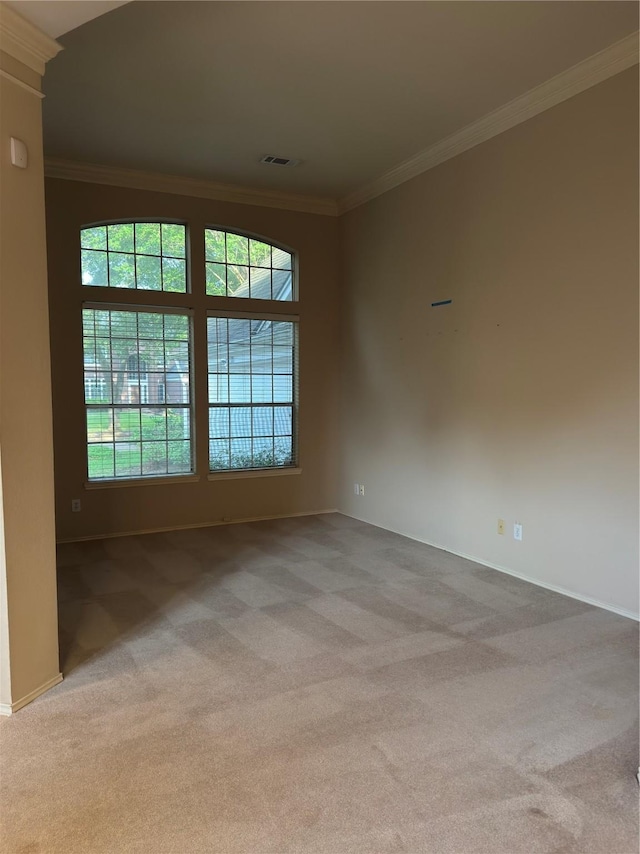 empty room with crown molding, carpet floors, baseboards, and visible vents