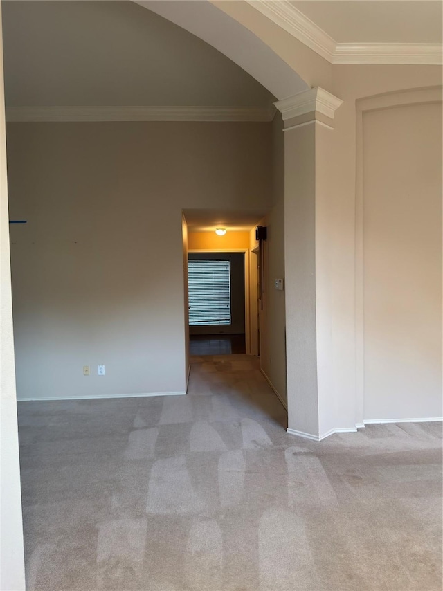 carpeted empty room featuring baseboards, ornamental molding, decorative columns, and arched walkways