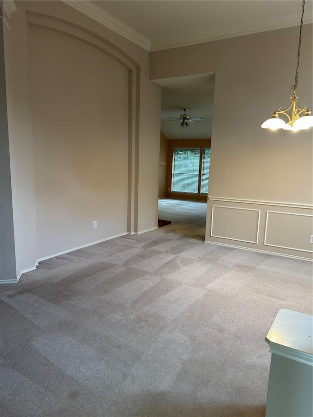 empty room featuring carpet floors, crown molding, and ceiling fan with notable chandelier