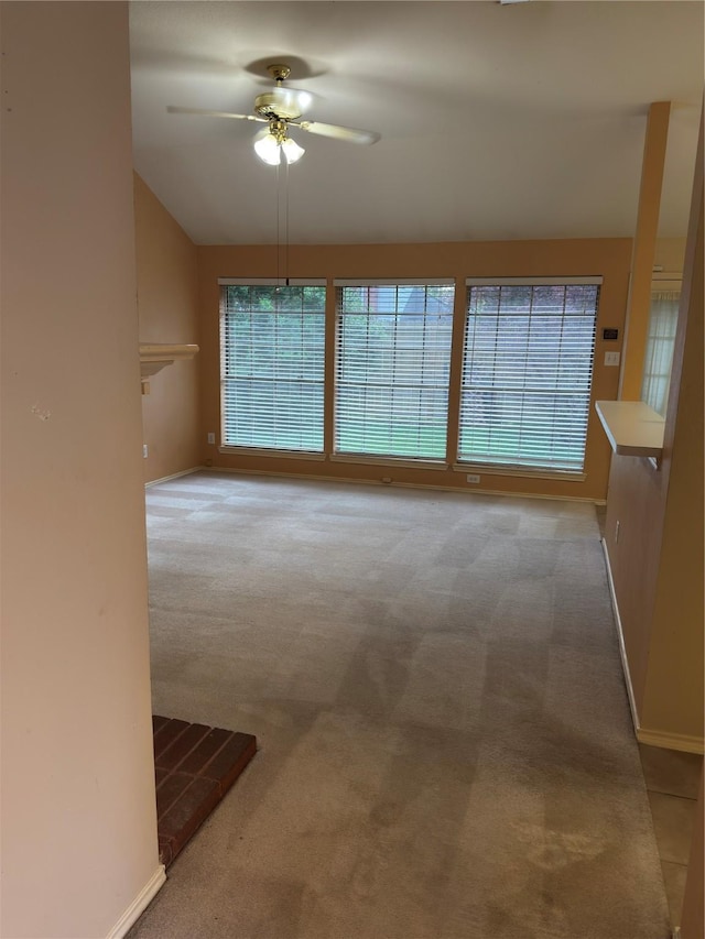 carpeted spare room featuring baseboards and ceiling fan