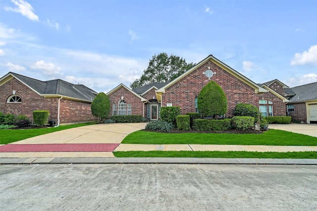 view of front of house featuring concrete driveway, brick siding, and a front lawn