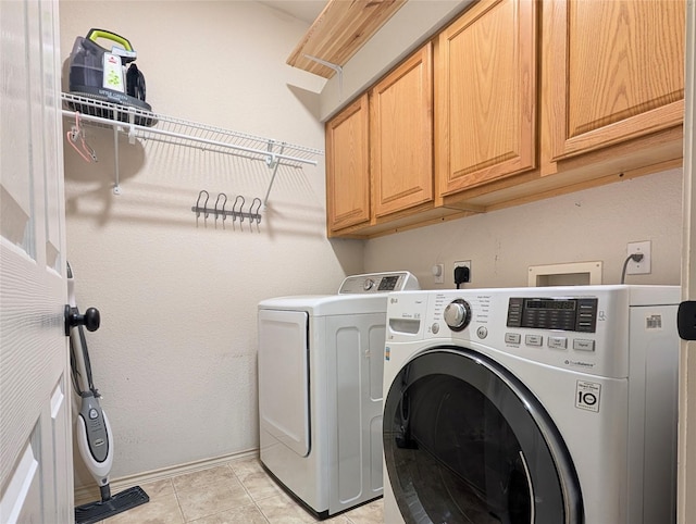 washroom featuring baseboards, washer and clothes dryer, cabinet space, and light tile patterned floors