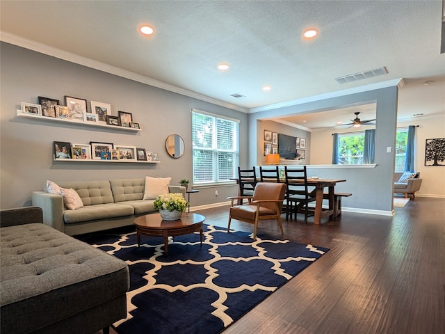 living room with visible vents, ornamental molding, wood finished floors, baseboards, and a ceiling fan