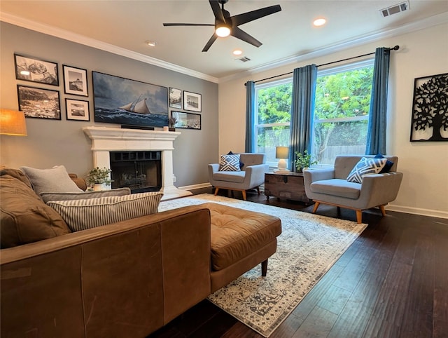 living area with visible vents, crown molding, a fireplace, baseboards, and a ceiling fan