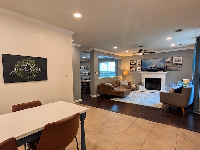 living area featuring crown molding, visible vents, ceiling fan, recessed lighting, and a fireplace with raised hearth