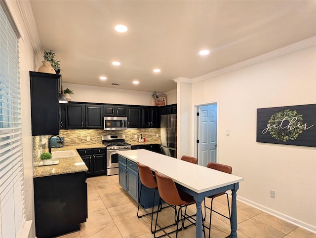 kitchen featuring a breakfast bar area, appliances with stainless steel finishes, a sink, ornamental molding, and dark cabinetry
