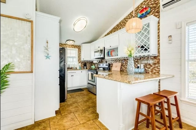 16530 Jean Lafitte Rd, Jamaica Beach, TX 77554 - kitchen featuring a peninsula, white cabinetry, tasteful backsplash, vaulted ceiling, and stainless steel appliances