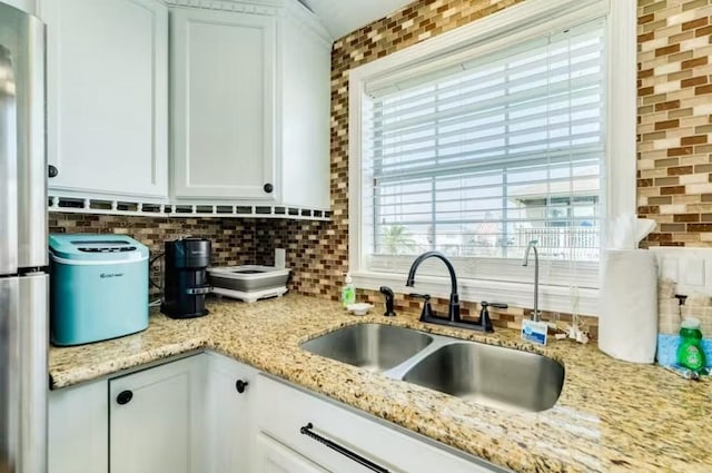 16530 Jean Lafitte Rd, Jamaica Beach, TX 77554 - kitchen featuring backsplash, a sink, light stone counters, freestanding refrigerator, and white cabinetry