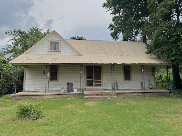 view of front facade featuring a chimney, a porch, and a front lawn