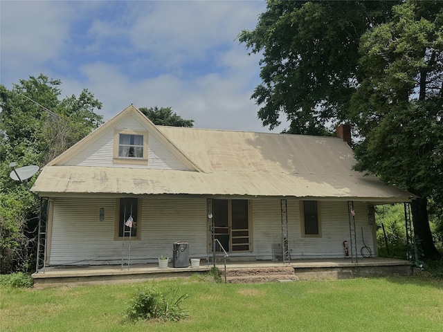 back of property featuring a lawn, a chimney, and a porch