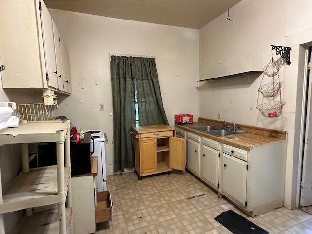 kitchen with white cabinets, open shelves, a sink, and light floors