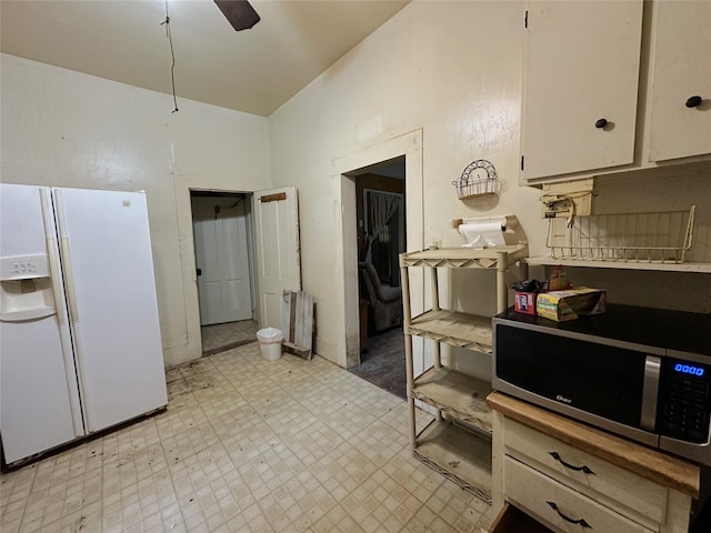 kitchen with light floors, white refrigerator with ice dispenser, stainless steel microwave, white cabinets, and a ceiling fan
