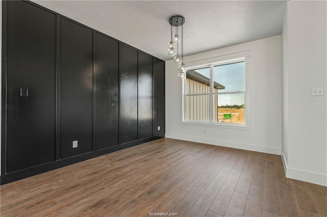 unfurnished dining area with baseboards and wood finished floors