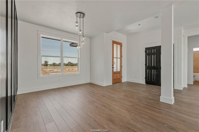 unfurnished dining area featuring a healthy amount of sunlight, baseboards, and wood finished floors