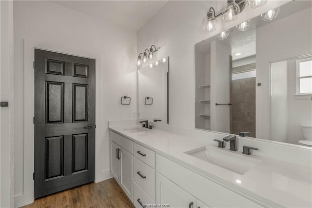 full bathroom with double vanity, a sink, wood finished floors, and toilet