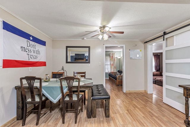 808 Morrell St, Baytown, TX 77520 - dining space featuring a ceiling fan, crown molding, a barn door, baseboards, and light wood-style floors