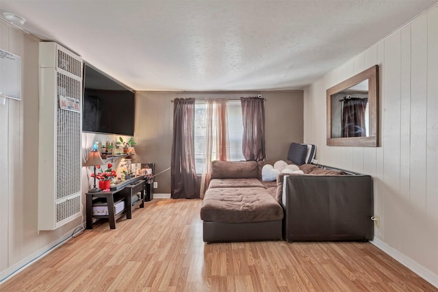808 Morrell St, Baytown, TX 77520 - living area featuring a textured ceiling, wood walls, baseboards, light wood-style flooring, and a heating unit