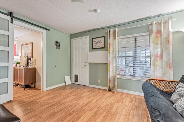 808 Morrell St, Baytown, TX 77520 - living area with a textured ceiling, a barn door, baseboards, and light wood finished floors