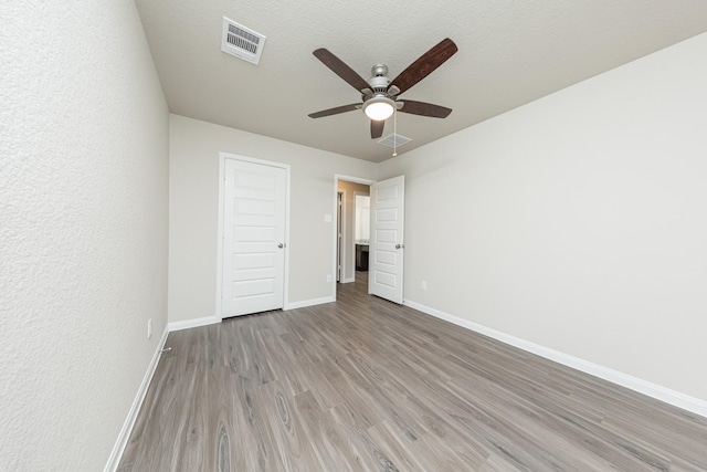 unfurnished bedroom featuring light wood-style floors, baseboards, ceiling fan, and visible vents