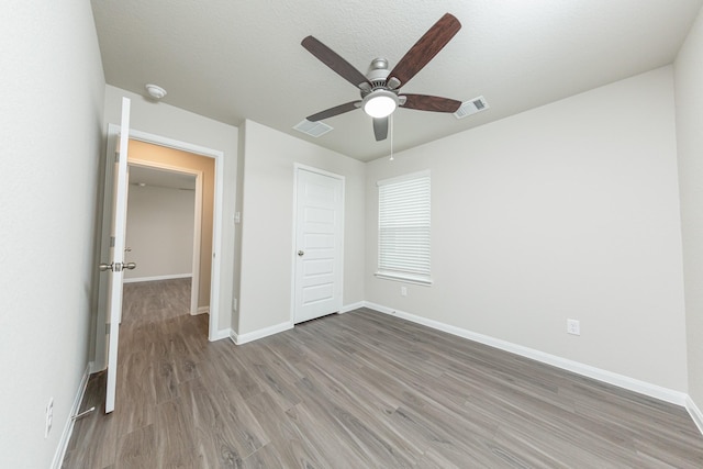 unfurnished bedroom with ceiling fan, baseboards, visible vents, and wood finished floors