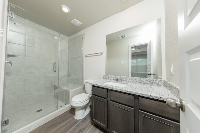 bathroom featuring toilet, a ceiling fan, wood finished floors, visible vents, and a stall shower