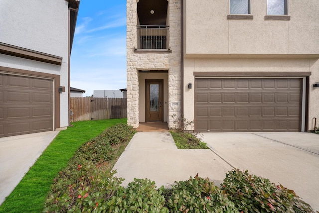 view of front of property featuring a garage, fence, stone siding, stucco siding, and driveway