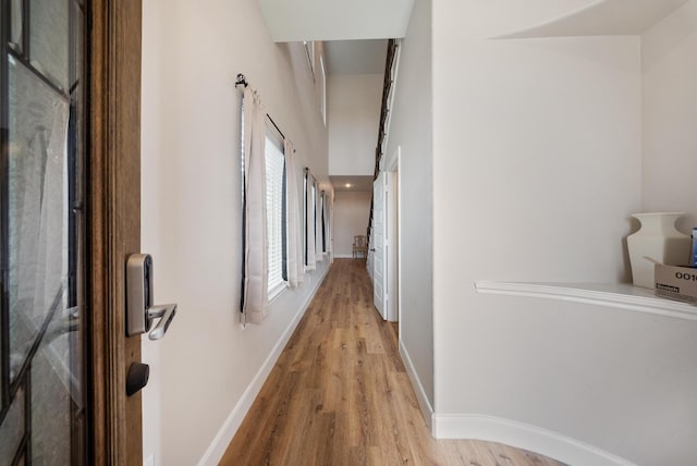 corridor with baseboards and light wood-type flooring