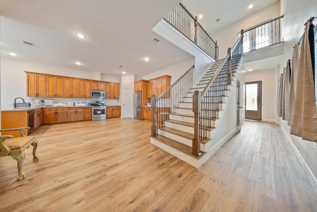 kitchen featuring visible vents, light countertops, brown cabinets, light wood-style flooring, and stainless steel appliances