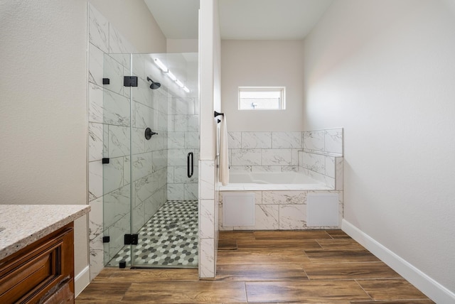 full bathroom with vanity, wood finished floors, baseboards, a bath, and a shower stall