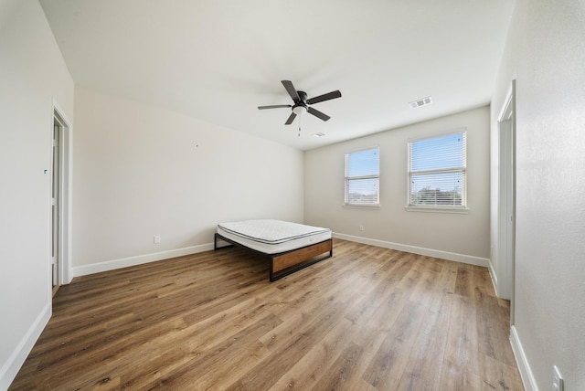 unfurnished bedroom with a ceiling fan, baseboards, visible vents, and wood finished floors