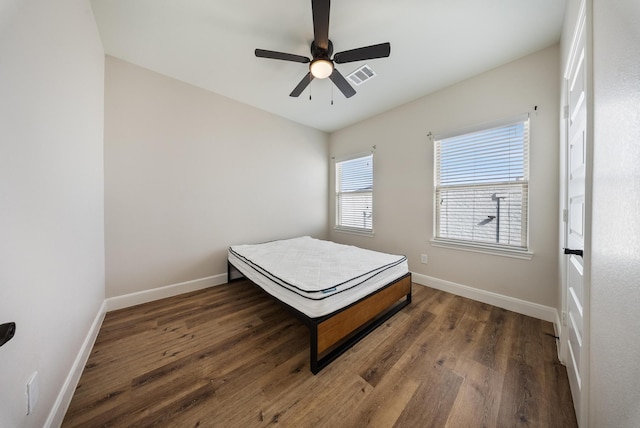 bedroom featuring visible vents, baseboards, ceiling fan, and wood finished floors