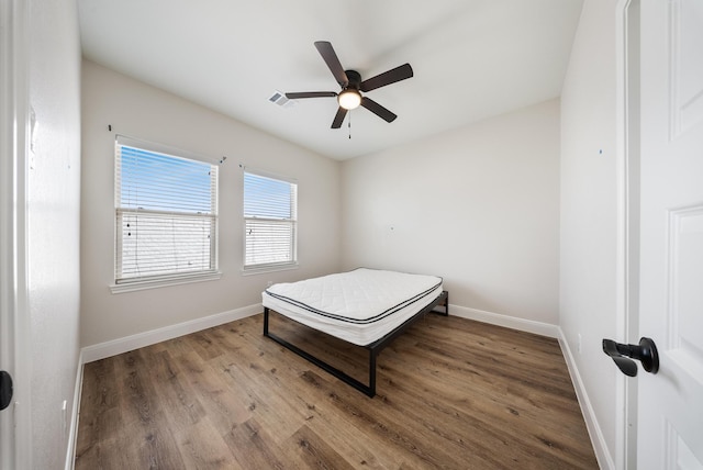 bedroom with ceiling fan, baseboards, visible vents, and wood finished floors