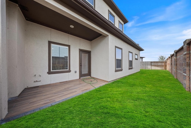 back of house with a lawn, a fenced backyard, stucco siding, and a deck