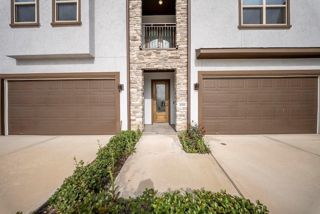 view of front of home featuring a garage, stucco siding, driveway, and stone siding