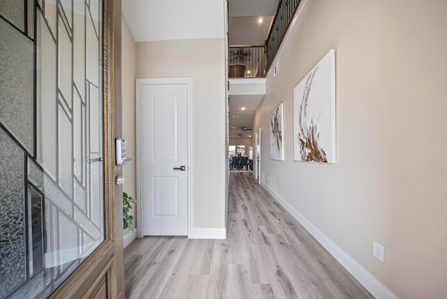entrance foyer featuring a towering ceiling, baseboards, and light wood-type flooring