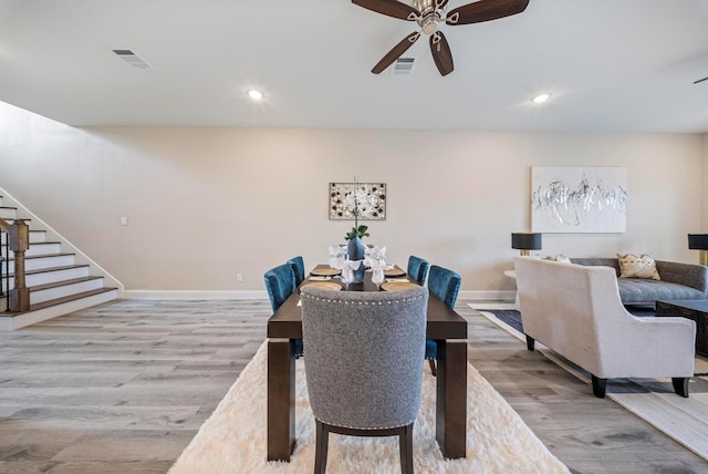 dining space with stairs, a ceiling fan, baseboards, wood finished floors, and visible vents