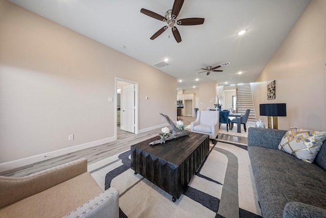 living area featuring light wood-style floors, a ceiling fan, baseboards, lofted ceiling, and visible vents